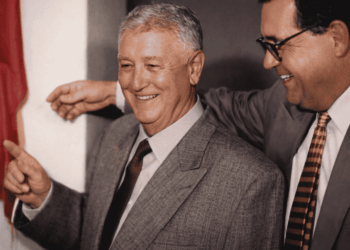 Mauro Ribeiro sorrindo em evento oficial em Itabira ao lado de outro homem de terno