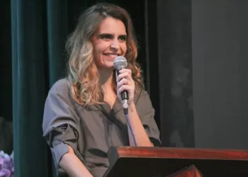 Raquell Guimarães falando ao microfone em evento em Itabira