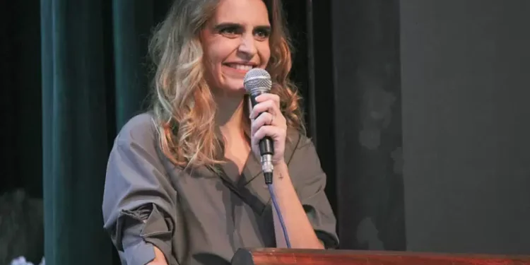 Raquell Guimarães falando ao microfone em evento em Itabira
