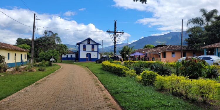 Vista do centro da Serra dos Alves, em Itabira, com capela azul e branca, casas antigas, jardim e montanhas ao fundo