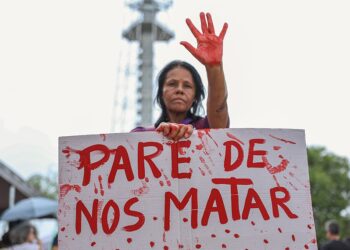 Mulher segura cartaz com a frase “Pare de nos matar” em protesto contra feminicídio e violência contra a mulher em Itabira