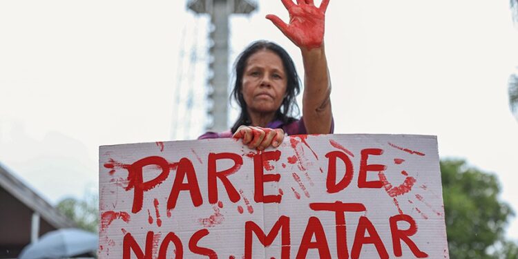 Mulher segura cartaz com a frase “Pare de nos matar” em protesto contra feminicídio e violência contra a mulher em Itabira