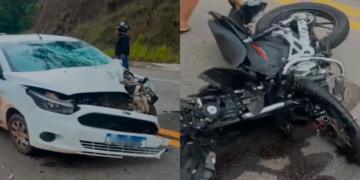Carro branco com a frente danificada e motocicleta caída após acidente na MG-129, perto da Rampa do Voo Livre, em Itabira.