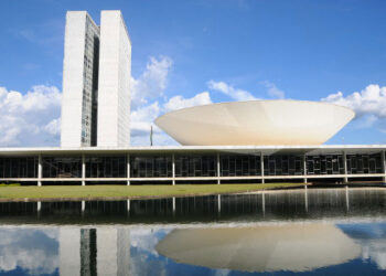 Prédio do Congresso Nacional, em Brasília, com torres e cúpula refletidas no espelho d’água, usado em notícia sobre deputados de Minas e escala 6x1.