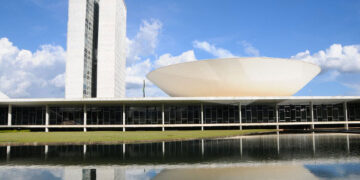 Prédio do Congresso Nacional, em Brasília, com torres e cúpula refletidas no espelho d’água, usado em notícia sobre deputados de Minas e escala 6x1.