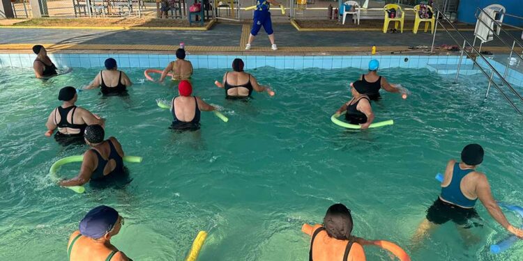 Idosos participam de aula de hidroginástica em piscina durante atividade de convivência e bem-estar