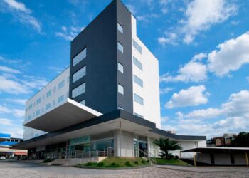Fachada do Premium Executive Hotel em Itabira, com prédio moderno, céu azul e área de entrada do hotel.