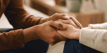 Mãos de duas pessoas em gesto de apoio e acolhimento durante conversa sobre saúde mental