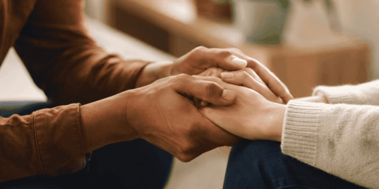Mãos de duas pessoas em gesto de apoio e acolhimento durante conversa sobre saúde mental